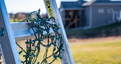Prep for installing Christmas lights by leaning a ladder against a house and setting out lights