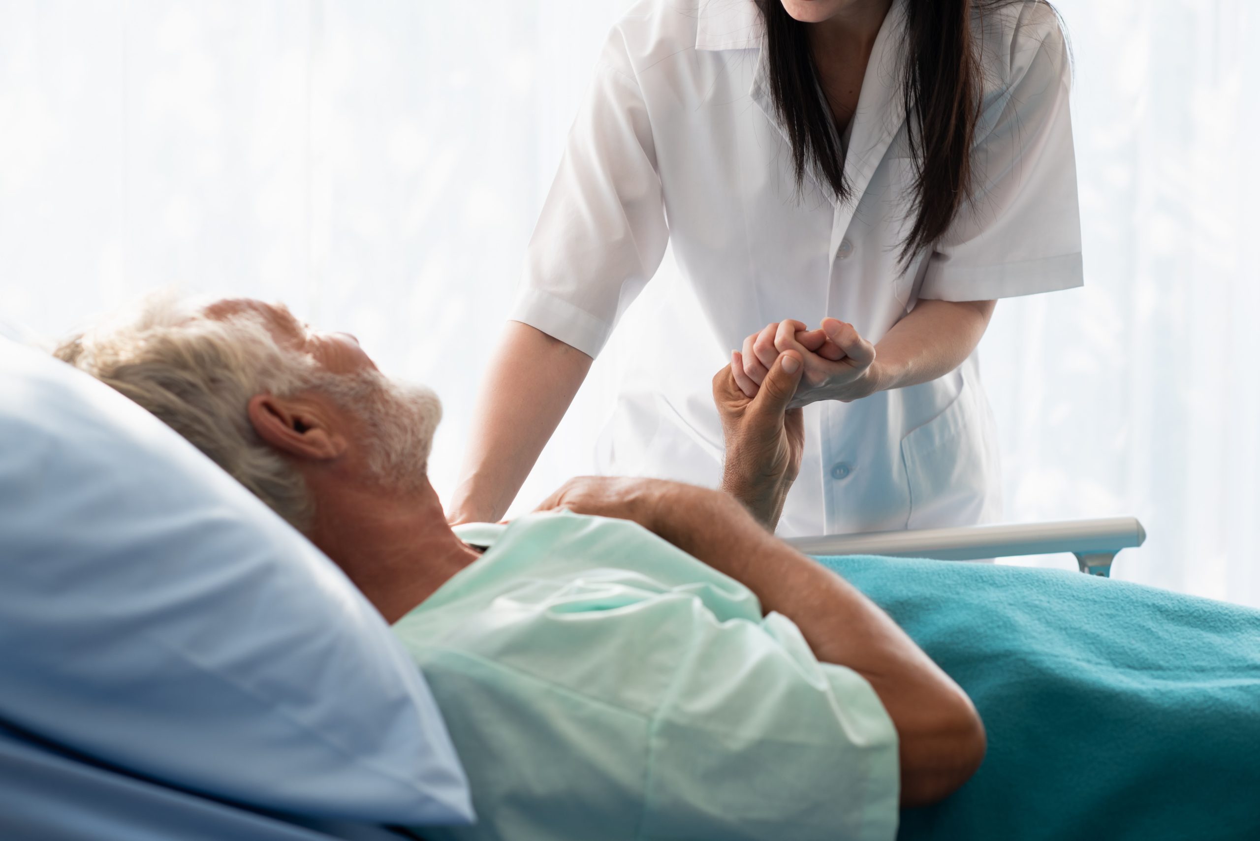 Nurse caring for patient in hospital bed.