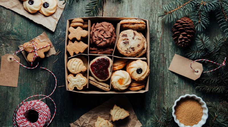 Holiday food background for baking gingerbread cookies in a small paper box decorated on rustic green table. Top view on cookies.