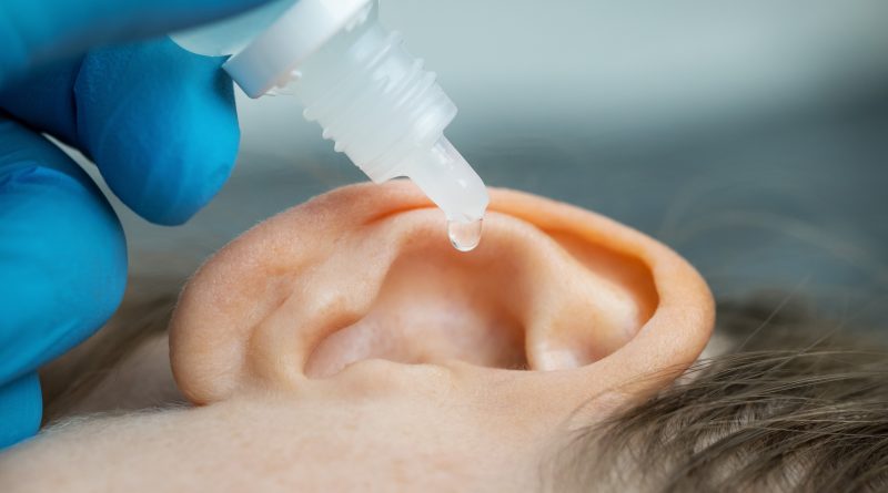 doctor dripping ear drops into patient ear. ear pain and clogged ears concept