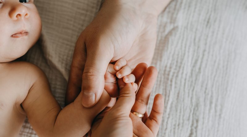 Parents holding newborn baby hand.