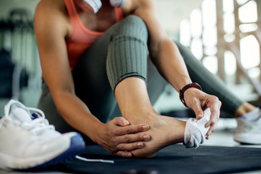 Woman holding foot at gym.
