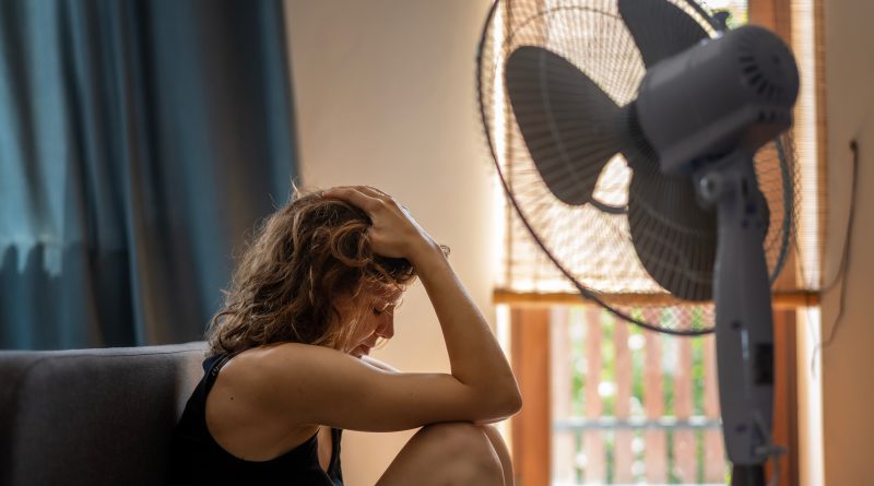 Woman sitting under fan.