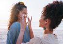 Mother, girl and sunscreen application at beach for uv protection, care and love on vacation in summer. Mom, child and lotion for face, skincare and bonding with smile by ocean on holiday.