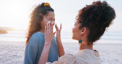 Mother, girl and sunscreen application at beach for uv protection, care and love on vacation in summer. Mom, child and lotion for face, skincare and bonding with smile by ocean on holiday.