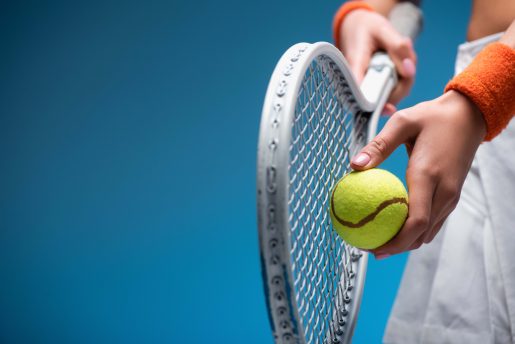 Person holding tennis racket and ball.