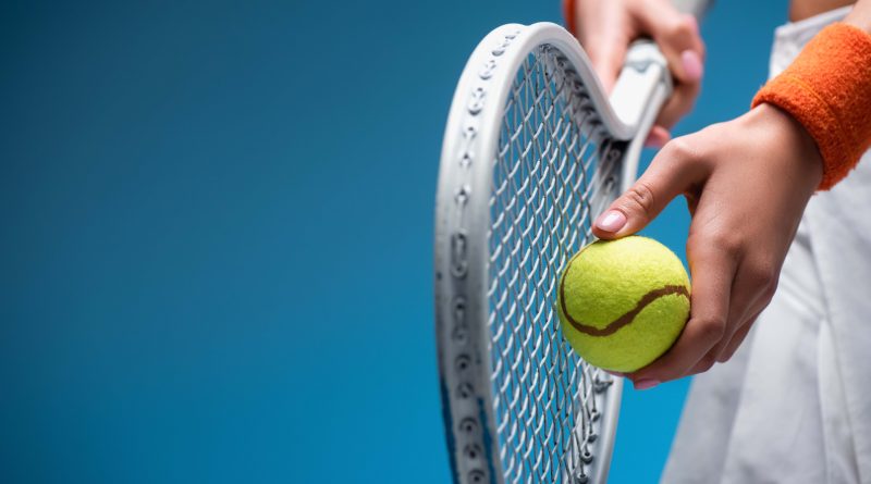 Person holding tennis racket and ball.